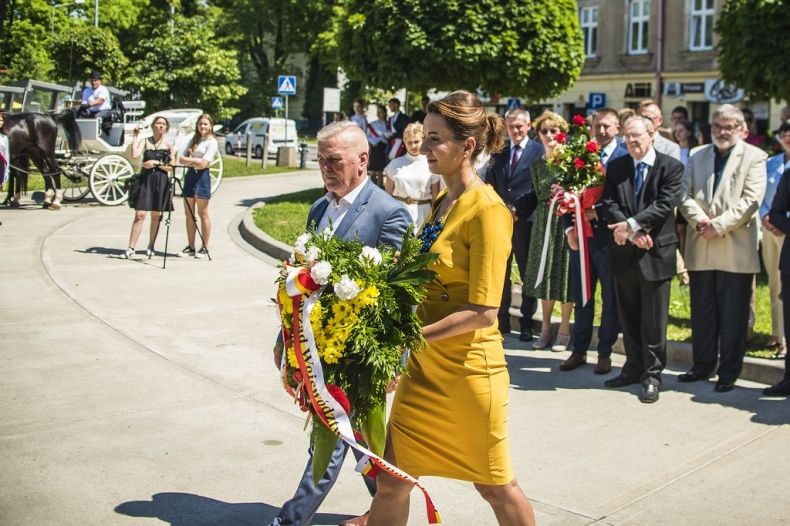Marta Malec-Lech z zarządu województwa składa wieniec przed pomnikiem. Obok idzie mężczyzna.