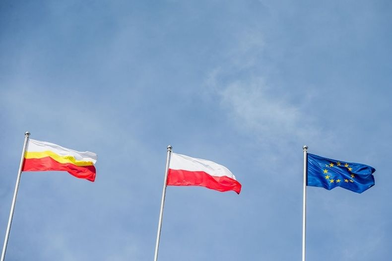 Flagi Województwa Małopolskiego, Polski i Unii Europejskiej na tle nieba