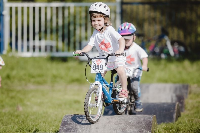 Zdjęcie przedstawia dwójkę dzieci na rowerkach uczestniczących w Małopolska Tour w 2021
