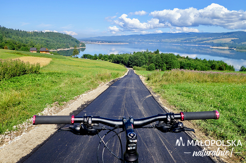 Trasa rowerowa w otoczeniu zieleni i górskiego krajobrazu, widziana zza kierownicy roweru