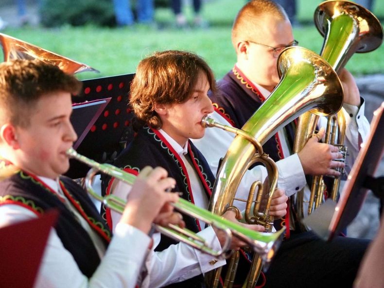 Chłopcy w strojach regionalnych grający na instrumentach dętych.