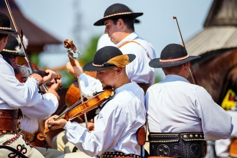 Mężczyźni w strojach regionalnych trzymający instrumenty muzyczne