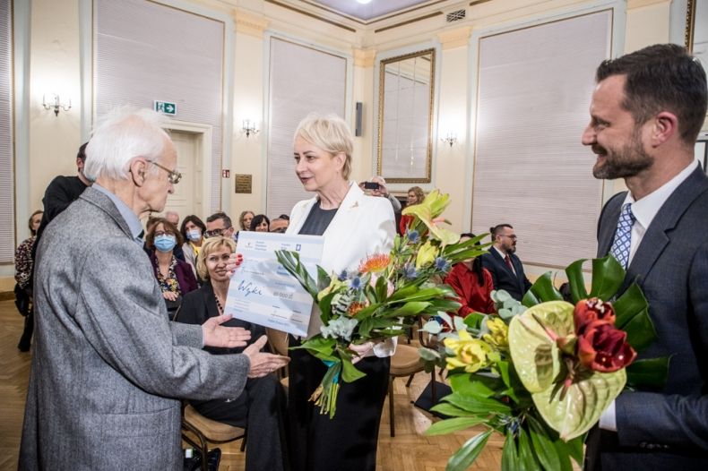 Iwona Gibas z zarządu województwa wręcza nagrodę i kwiaty.