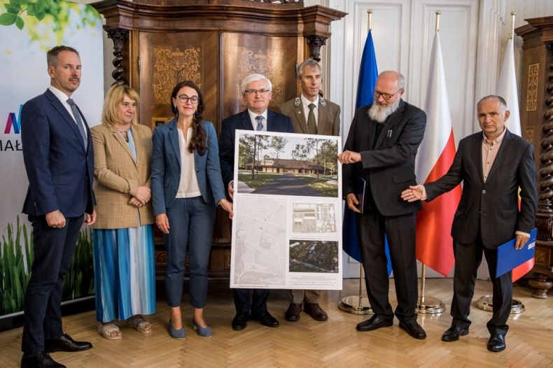 Uczestnicy spotkania prezentują planszę ze zwycięskim projektem budynku