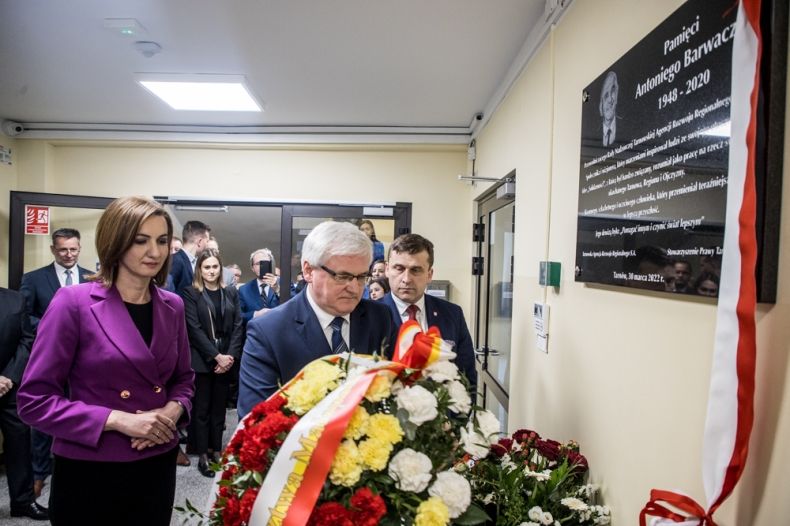 Wicemarszałek Józef Gawron i Marta Malec-Lech z zarządu województwa składają wieniec z kwiatów przed tablicą.