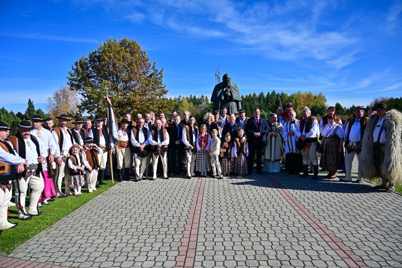 uczestnicy uroczystości w zbiorowym zdjęciu przed pomnikiem Jana Pawła II