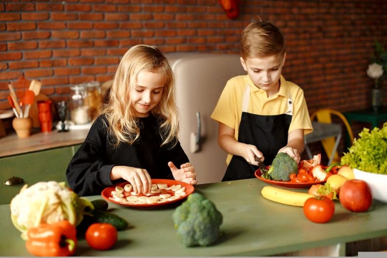 Dzieci przygotowują w kuchni posiłek z owoców i warzyw