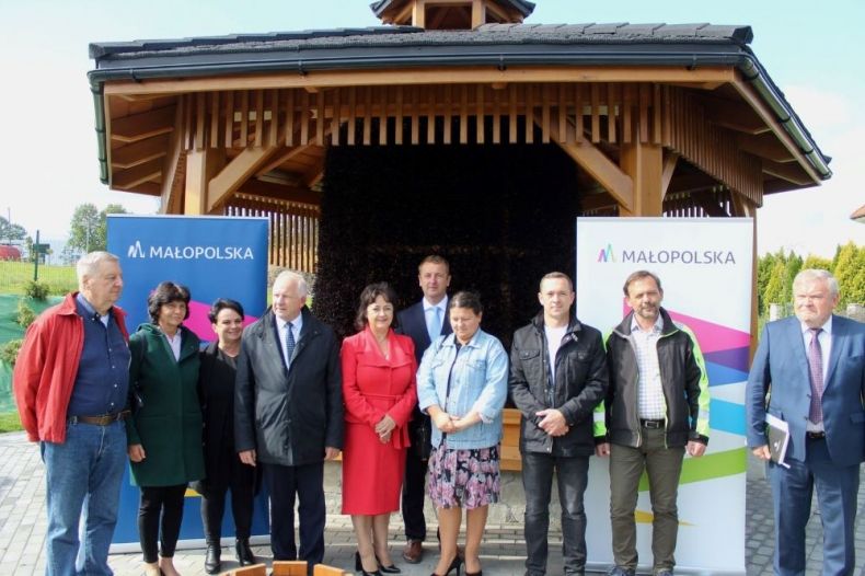 Uczestnicy wydarzenia stoją przed tężnią. Z tyłu banery z napisem Małopolska.