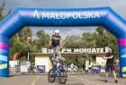 Rowerzysta wykonuje akrobacje na linii startu rajdu, w tle balonowa bramka z napisem "Małopolska"