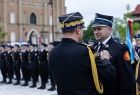 Wicemarszałek Łukasz Smółka stoi na rynku i przyjmuje odznaczenie.