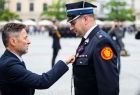 Mężczyzna przypina medal do munduru wicemarszałkowi Łukaszowi Smółce.