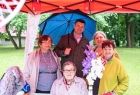 Wicemarszałek Łukasz Smółka trzyma parasol i stoi ze starszymi kobietami.