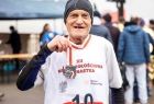 Senior w sportowej koszulce trzyma w ręce medal.