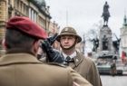 Żołnierze salutują sobie wzajemnie. Z tyłu widoczny pomnik na Placu Matejki w Krakowie.