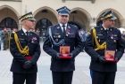 Wicemarszałek Łukasz Smółka stoi i trzyma w rękach pamiątkowy medal.