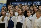 Dzieci w eleganckich strojach śpiewają podczas uroczystości