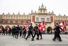 Strażacy idą ze sztandarami po płycie Rynku Głównego.