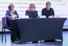 Widok na trzy specjalistki do spraw środków unijnych. Kobiety siedzą przy stole ustawionym na scenie. 