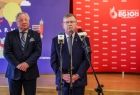 Marszałek Witold Kozłowski przy mikrofonie. W tle logotyp Igrzysk Europejskich. 