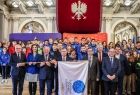 Marszałek Witold Kozłowski i oficjele trzymający flagę IE. W tle młodzież z klubów sportowych.