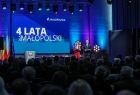 Widok na scenę z widowni. Na scenie widać wyświetlony napis 4 lata dla Małopolski. 
