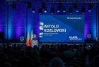 Widok z widowni na scenę, przy mównicy stoi marszałek Witold Kozłowski w tle widać tablicę multimedialną. 