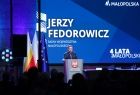 Marszałek Małopolski Witold Kozłowski przemawia do zgromadzonych gości. W tle wyświetlony jest pokaz slajdów. 