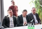 Trzech mężczyzn w garniturach siedzących przy stole.