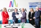 Marszałek Witold Kozłowski i mężczyzna w garniturze trzymający podpisaną umowę.