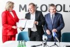 Poseł Józefa Szczurek Żelazko przekazuje umowę mężczyźnie. Obok marszałek Witold Kozłowski.