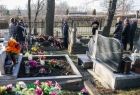 Widok na kilkanaście grobów żołnierzy wyklętych, na których złożono kwiaty, znicze i wieńce z szarfami w kolorach małopolski i polski. W tle widać pozostałych członków uroczystości. 