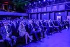 Zgromadzeni goście i uczestnicy wydarzenia siedzą w rzędach