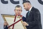 Marszałek Witold Kozłowski wręcza medal mężczyźnie w garniturze.