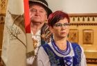 w tle góral ze sztandarem na pierwszym planie góralka w strojach regionalnych