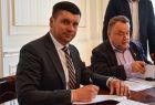 Wicemarszałek Łukasz Smółka siedzi przy stole i podpisuje umowę.