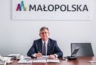 Marszałek Witold Kozłowski siedzi przy stole. Za nim na ścianie widoczny napis Małopolska.