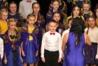 Dziewczynki i chłopcy w kolorowych strojach śpiewają na scenie