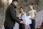 Wicemarszałek Łukasz Smółka podaję rękę dziewczynce na podium.