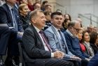 Wicemarszałek Łukasz Smółka siedzi na trybunach. Obok inni ludzie.