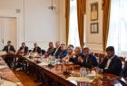 Uczestnicy wydarzenia siedzący przy stole. Na ścianie wisi portret Jana Pawła II.