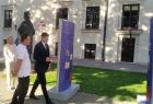 Wicemarszałek Łukasz Smółka idzie obok wystawy plenerowej. Obok widoczni ludzie i zieleń.