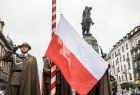 Flaga Polski wciągana na maszt przez żołnierzy.