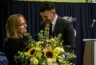 Wicemarszałek Łukasz Smółka wręcza kwiaty kobiecie.