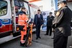 Wicemarszałek Łukasz Smółka stoi przy karetce, obok ratownik i strażacy.