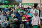 Grupa dzieci w zielonych strojach zachęca do segregowania śmieci