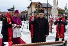 Ksiądz poświęca sztandar, w ręce trzyma kropidło.