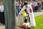 Radny województwa Mirosław Dróżdż ubrany w historyczne szaty składa kwiaty pod pomnikiem.