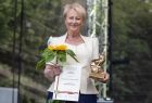 Iwona Gibas stoi na scenie trzymając kwiat słonecznika i statuetkę
