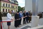 Radna Marta Mordarska, kapłan oraz trzech mężczyzn w garniturach przecinający biało-czerwoną wstęgę.
