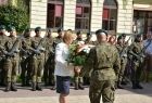 Radna Marta Mordarska przekazująca wiązankę kwiatów żołnierzowi.